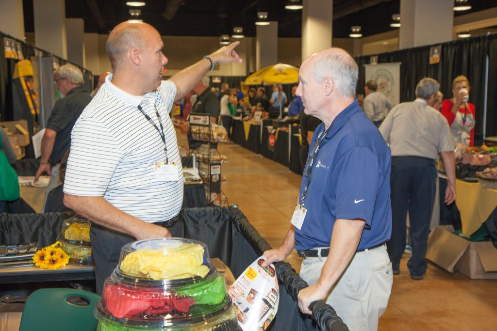 trade show picture of vendors at food table talking to customers