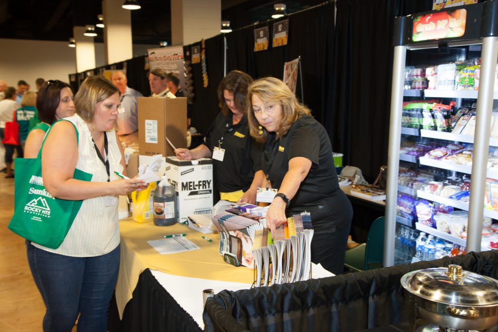 trade show picture of vendors at food table talking to customers