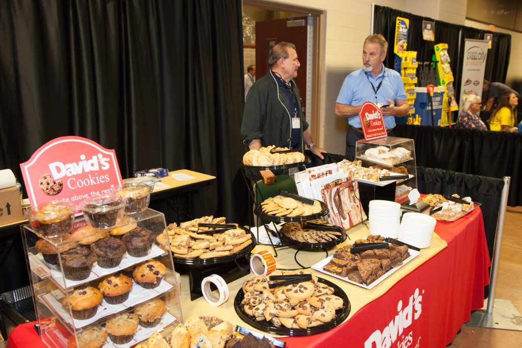 trade show picture of vendors at food table talking to customers